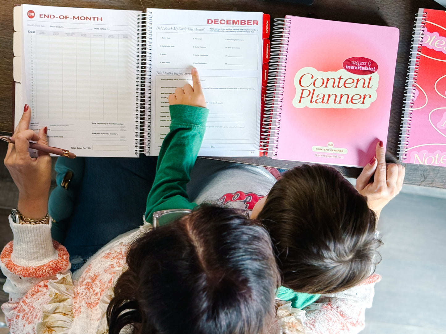 Two people looking at a planner with a pink 'Content Planner' in the foreground.