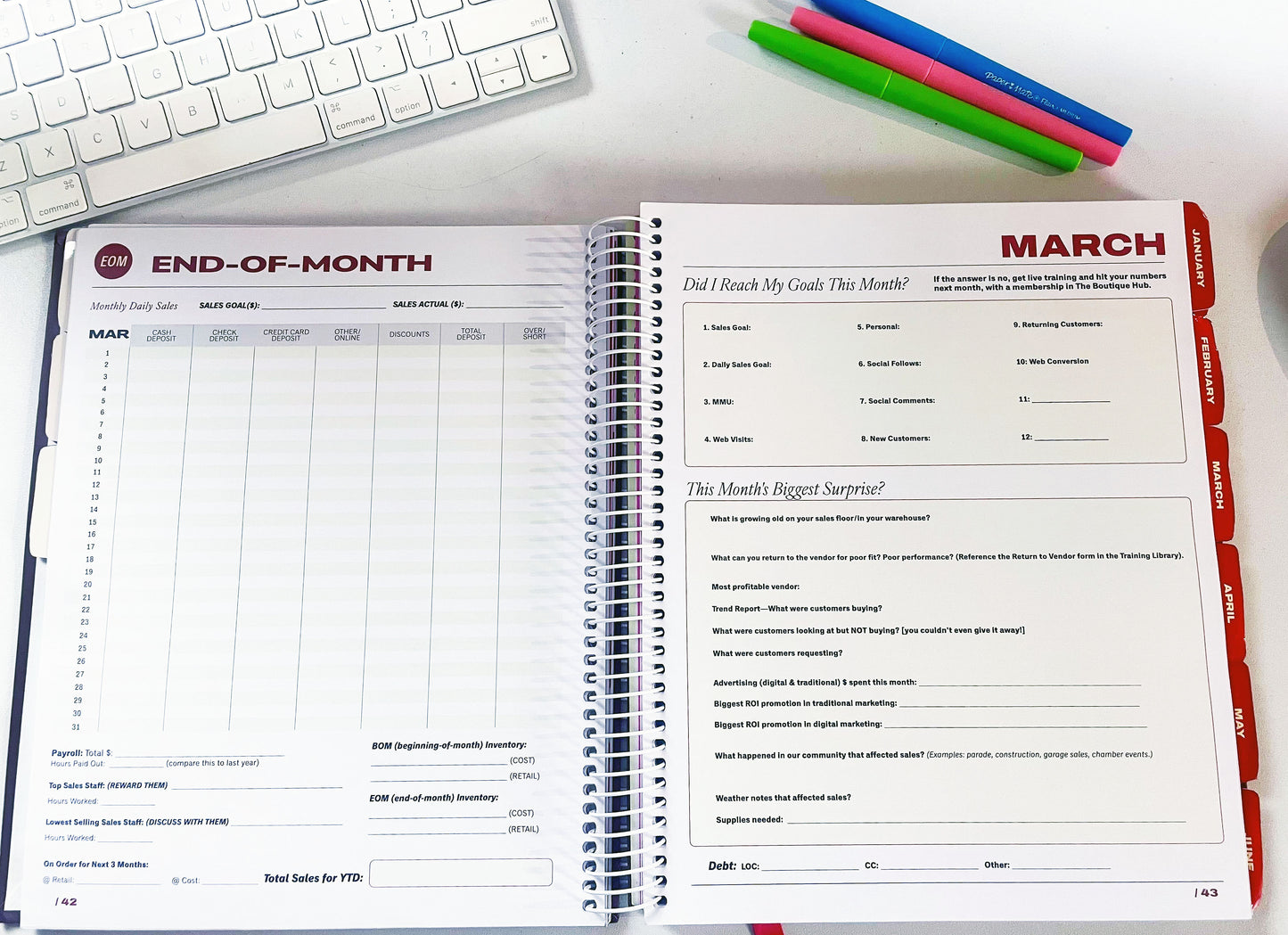 Open planner with monthly layout on a desk with a keyboard and pens.